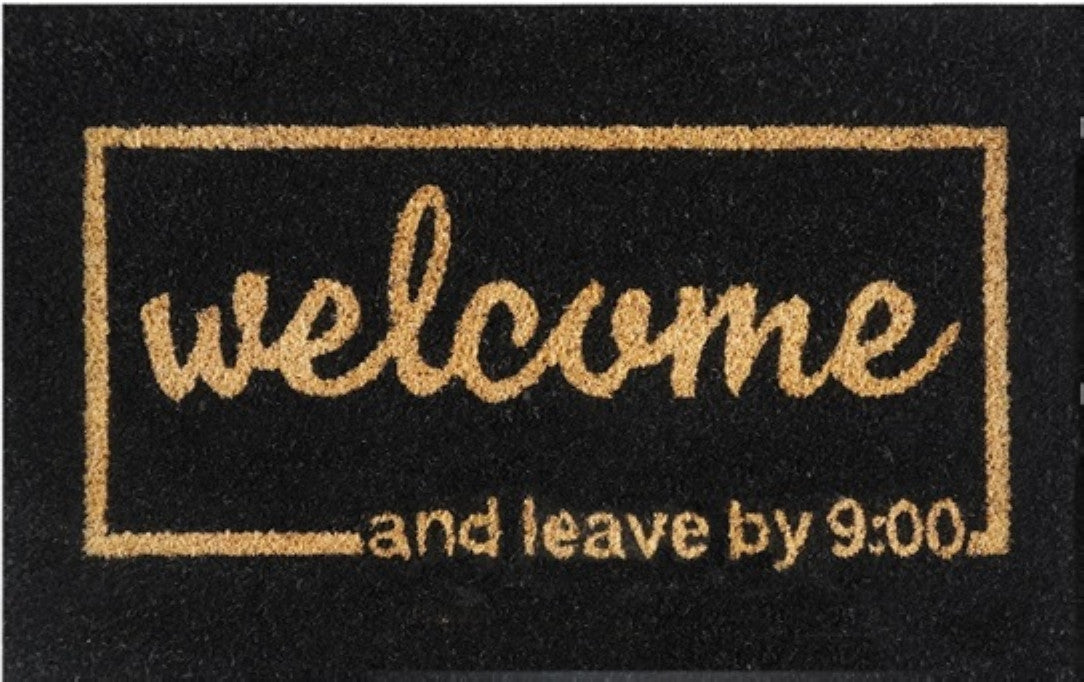 Black doormat close-up: 'Welcome' and 'Leave by 9:00' lettering