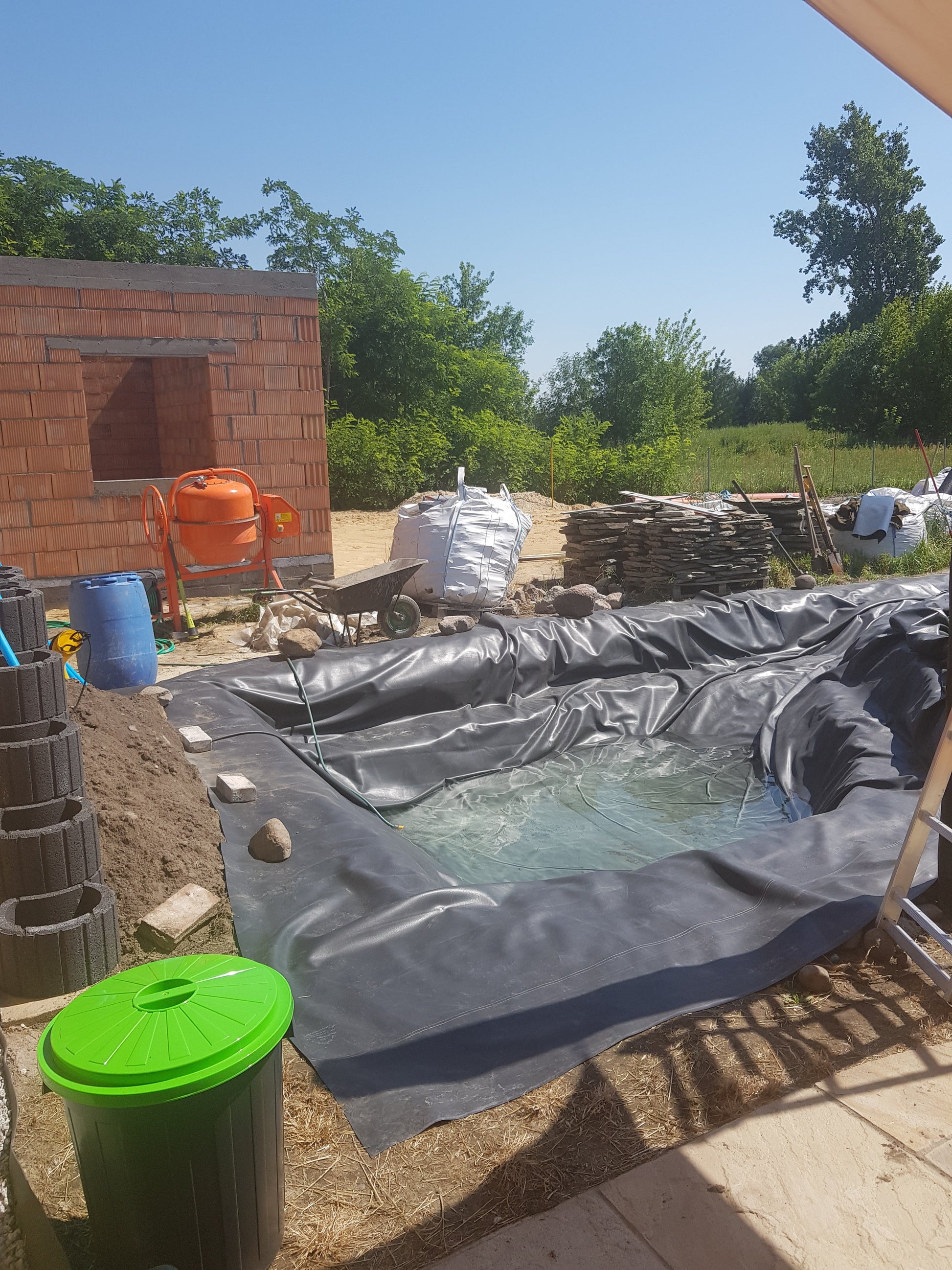 EPDM pond liner 6m x 6m, black sheet forming a pond bowl beside patio