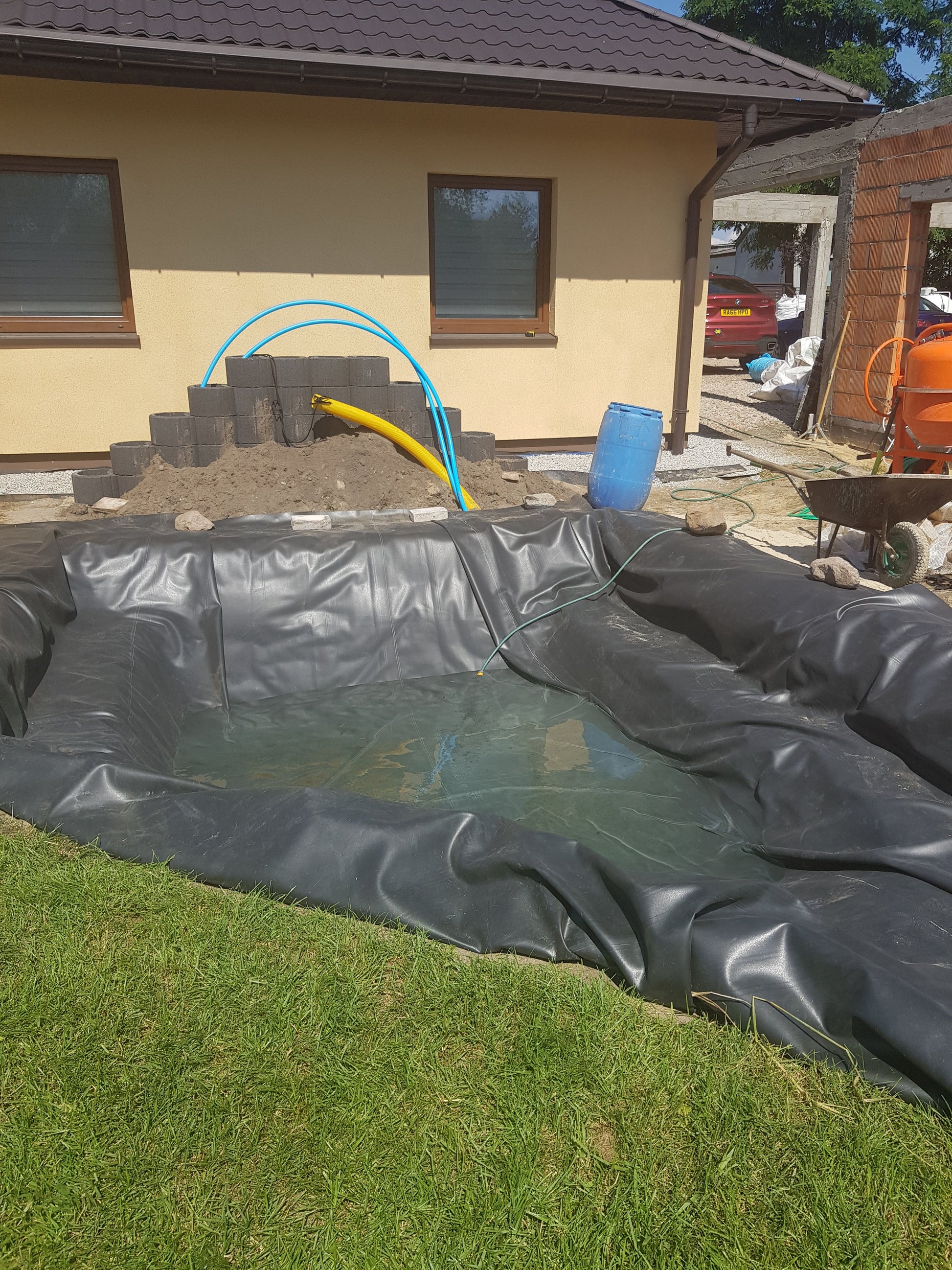 Black EPDM pond liner lining a rectangular pond edge during installation