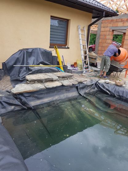Black EPDM pond liner at the pond edge, folded and laid over basin walls
