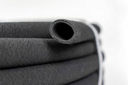 Porous soaker hose end close-up, dark rubber with open porous holes