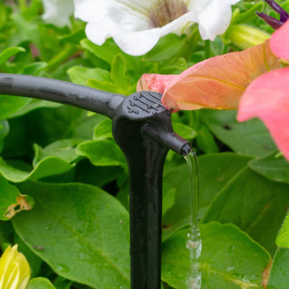 Black irrigation spike dripper releasing steady water flow from outlet