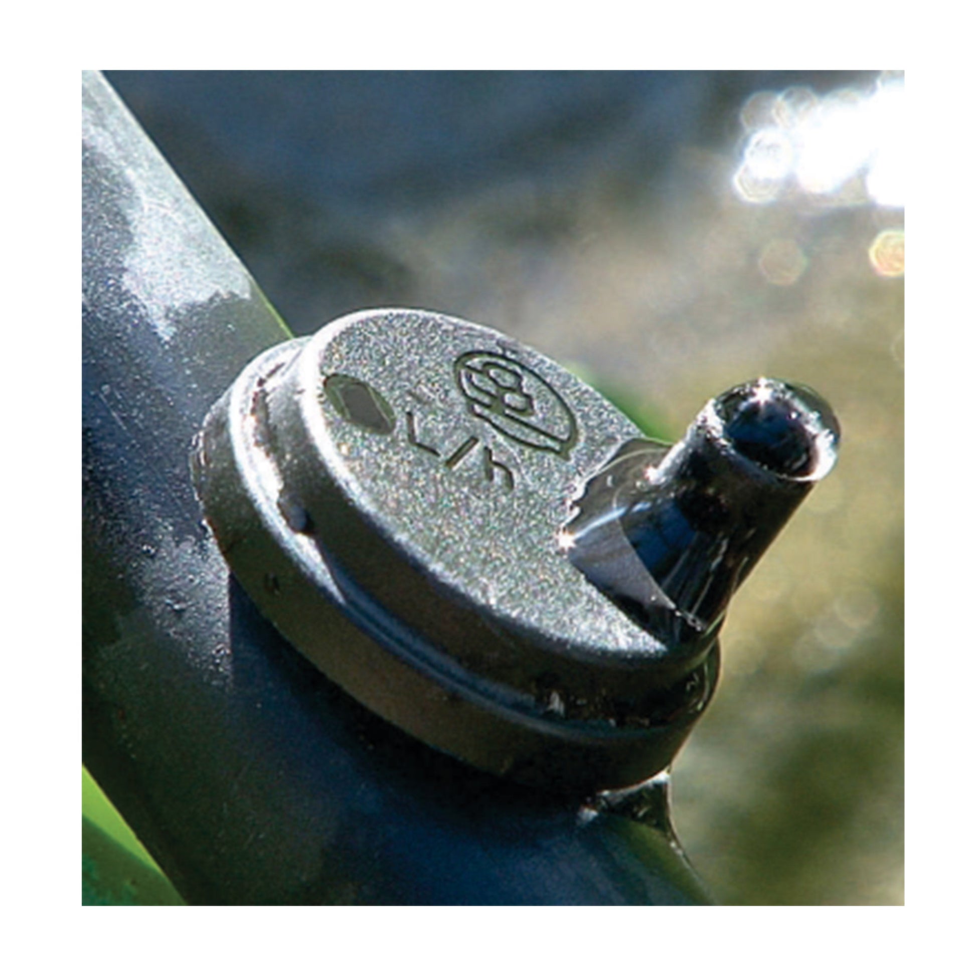 Black dripper cap close-up with inlet outlet spout, turbulent flow emitter