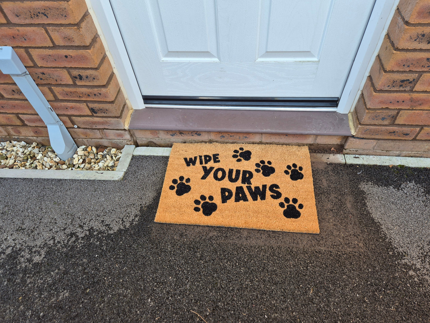 “WIPE YOUR PAWS” coir doormat with paw-print graphic on outdoor ground