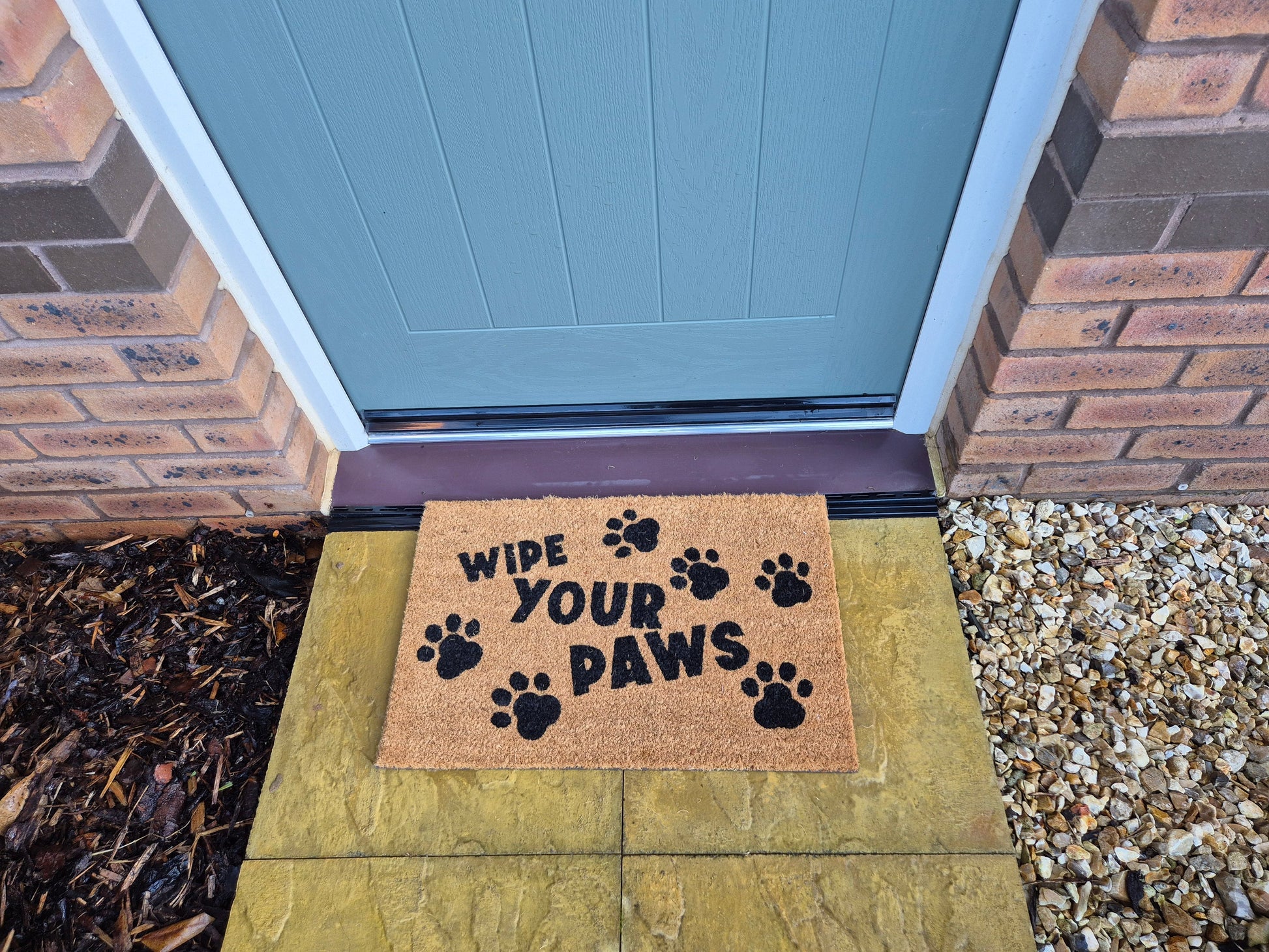Coir doormat “WIPE YOUR PAWS” with paw prints, placed at front door step