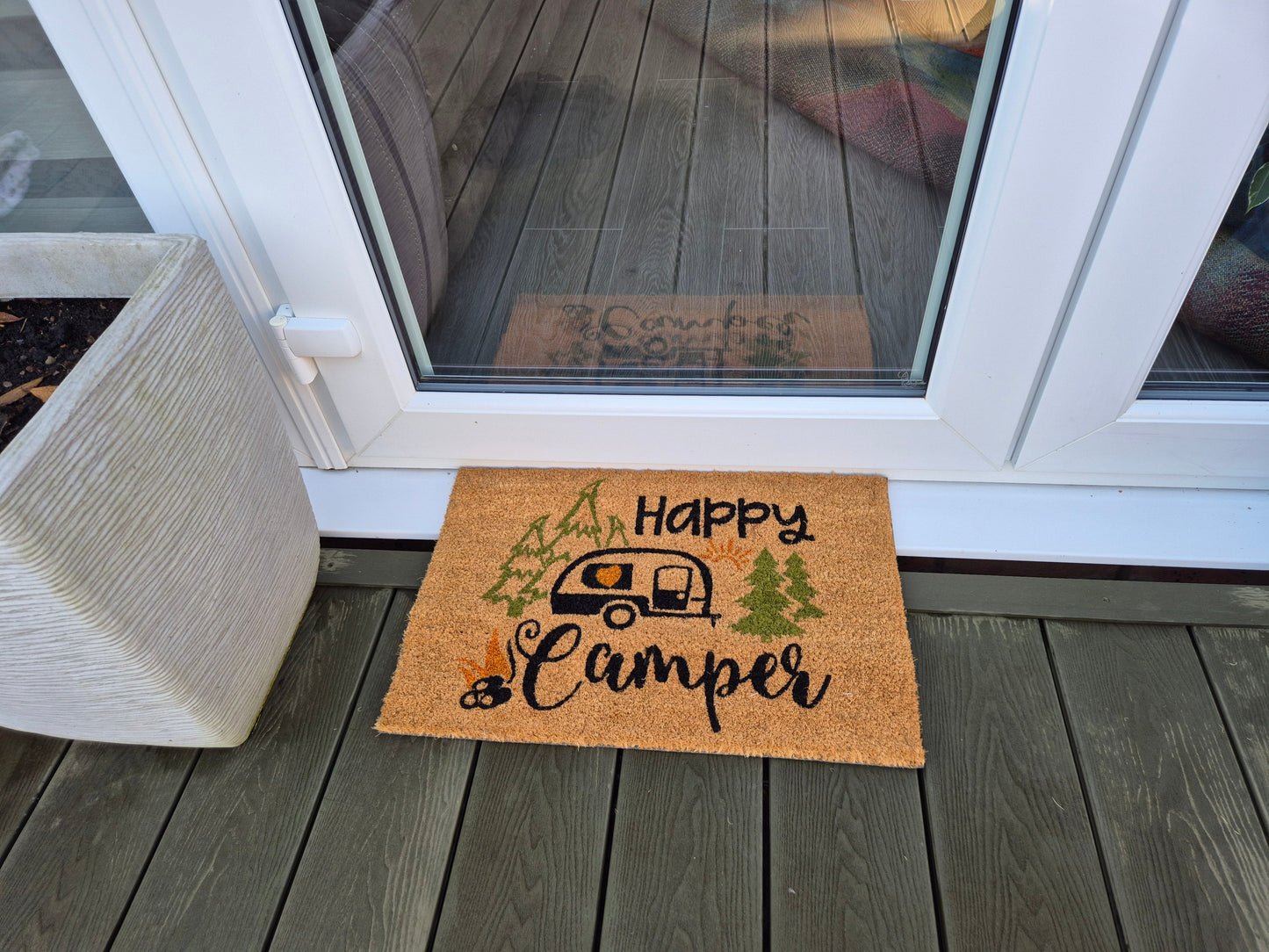 Outdoor “Happy Camper” coir doormat, orange-brown, on wooden porch