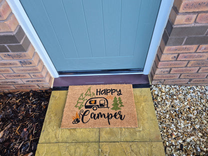 “Happy Camper” doormat on stepping stone walkway, caravan and forest design