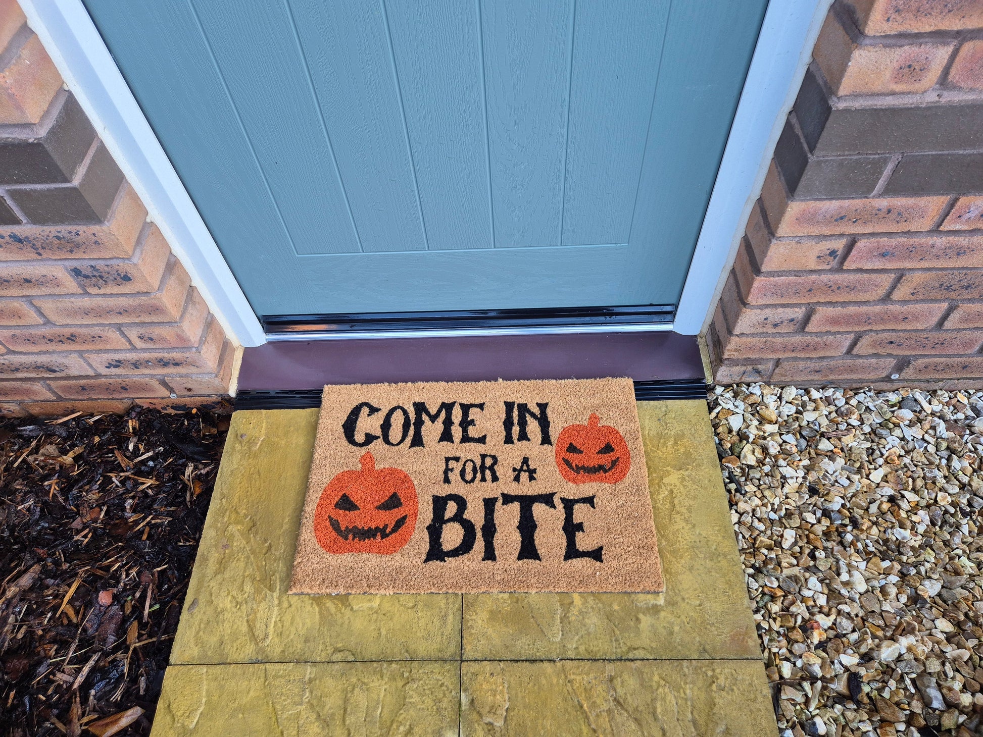 Brown doormat reading 'Come in for a Bite' with jack-o'-lantern graphics