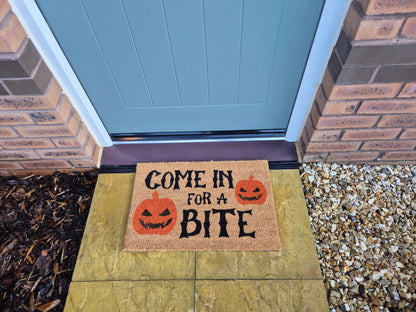 Brown doormat reading 'Come in for a Bite' with jack-o'-lantern graphics