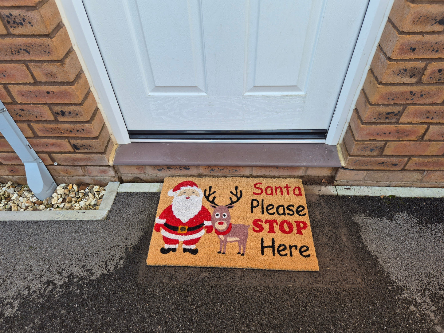 Holiday doormat on porch with Santa and reindeer and text “Santa Please STOP Here”