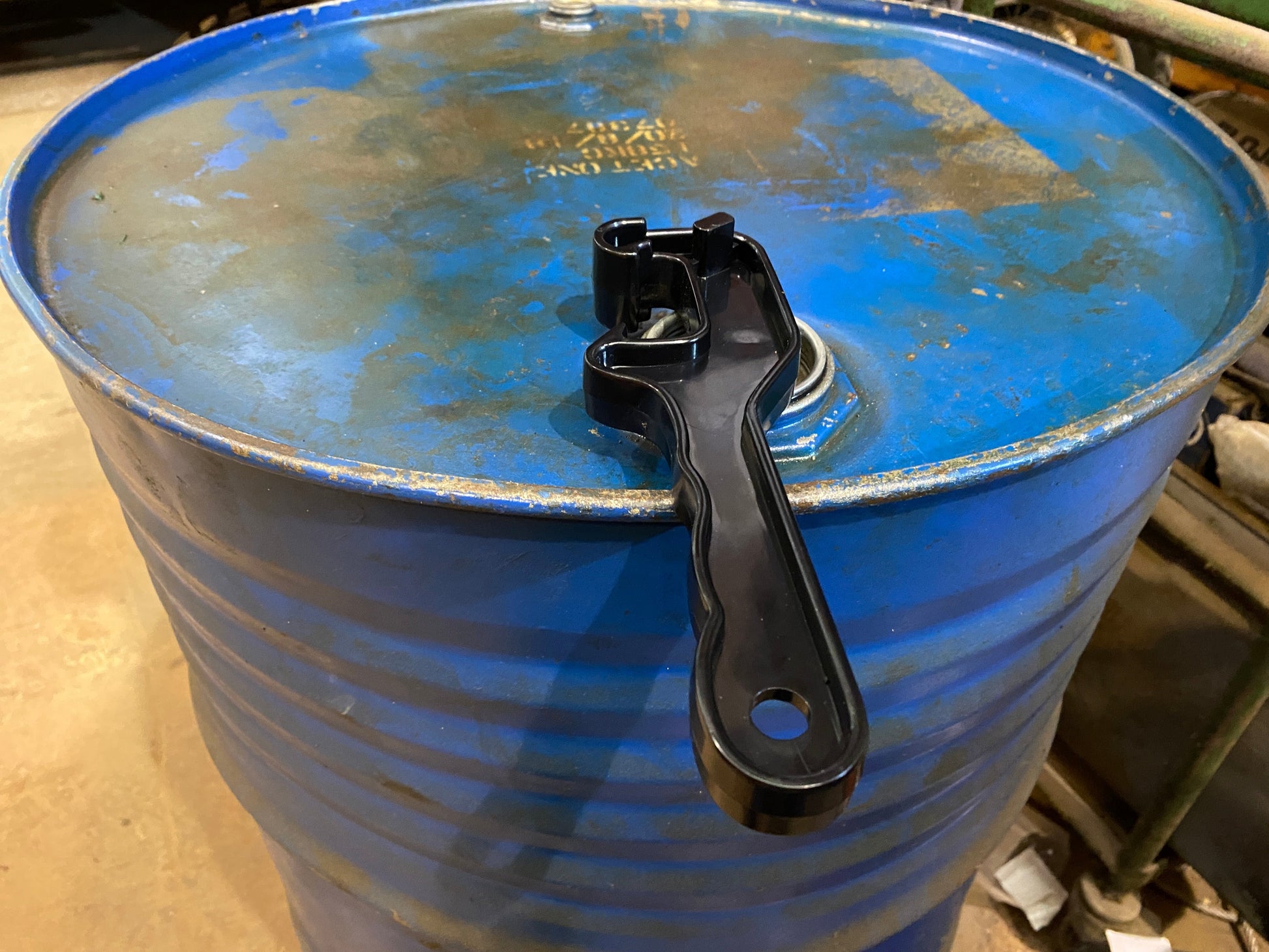 Universal drum wrench on top rim of oil drum, showing clamp on bung assembly