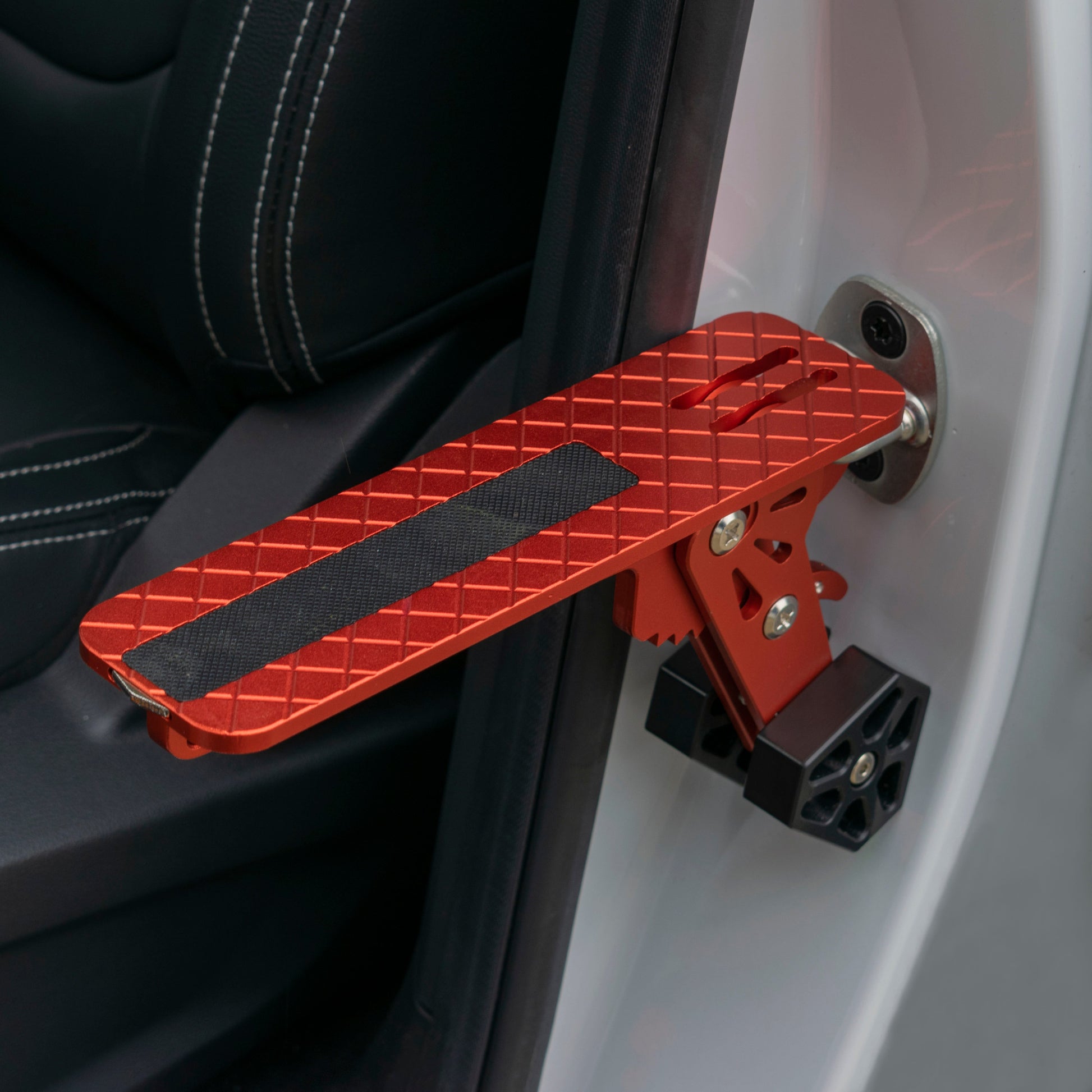 Orange folding car door step with black anti-slip strip and ridged grid tread
