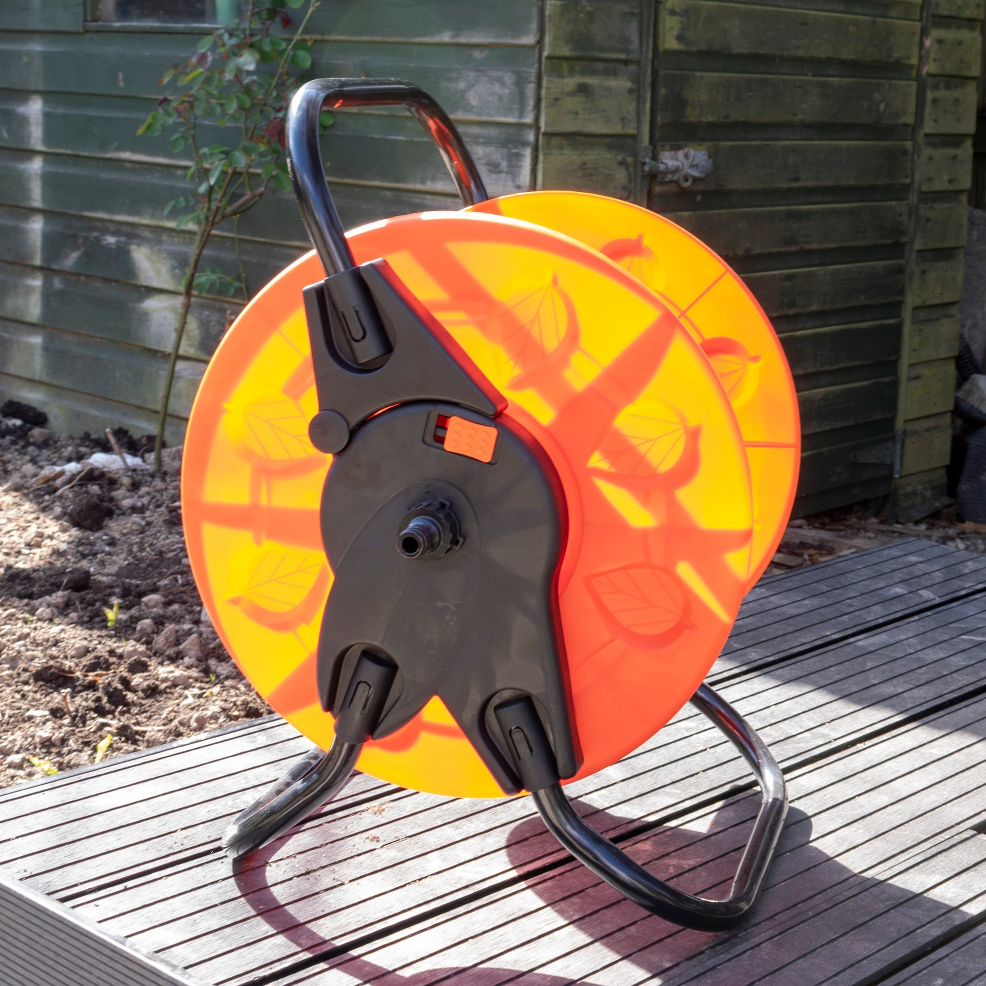 Close-up hose reel cart: orange drum with black connector housing and stand frame