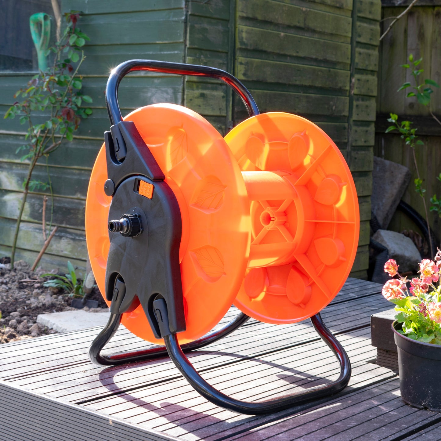 Outdoor garden hose reel cart with orange drum, black housing and curved stand
