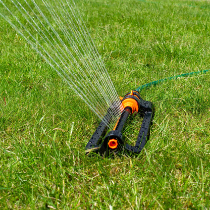 Oscillating sprinkler spraying a fine fan from the orange/black head