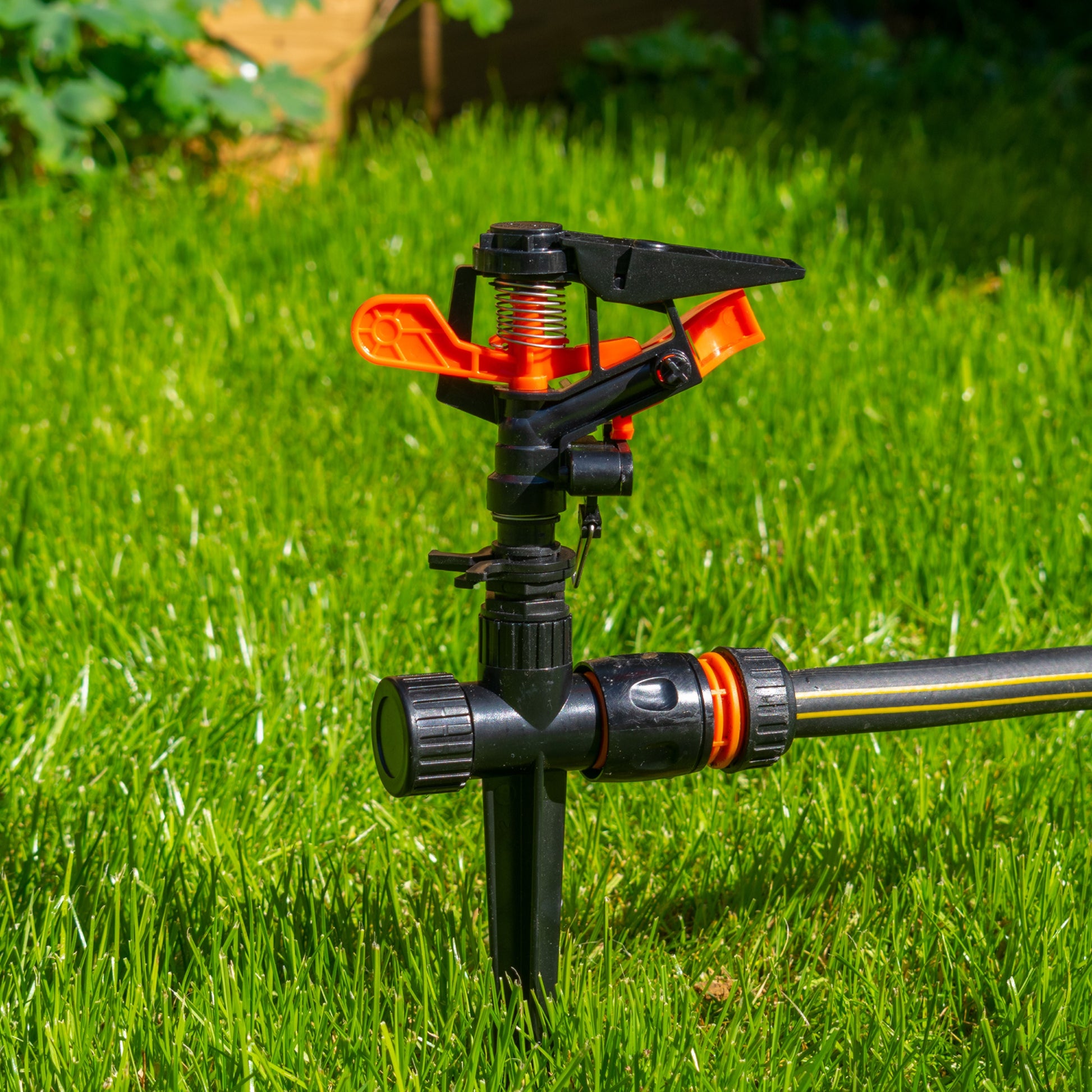 Pulsating sprinkler head on spike, black body with orange adjustment tabs
