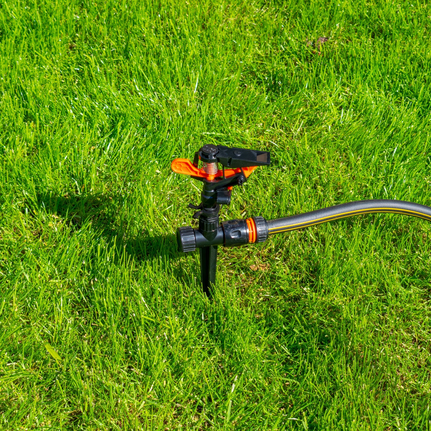 Sprinkler on spike with hose connection fitting, black and orange components