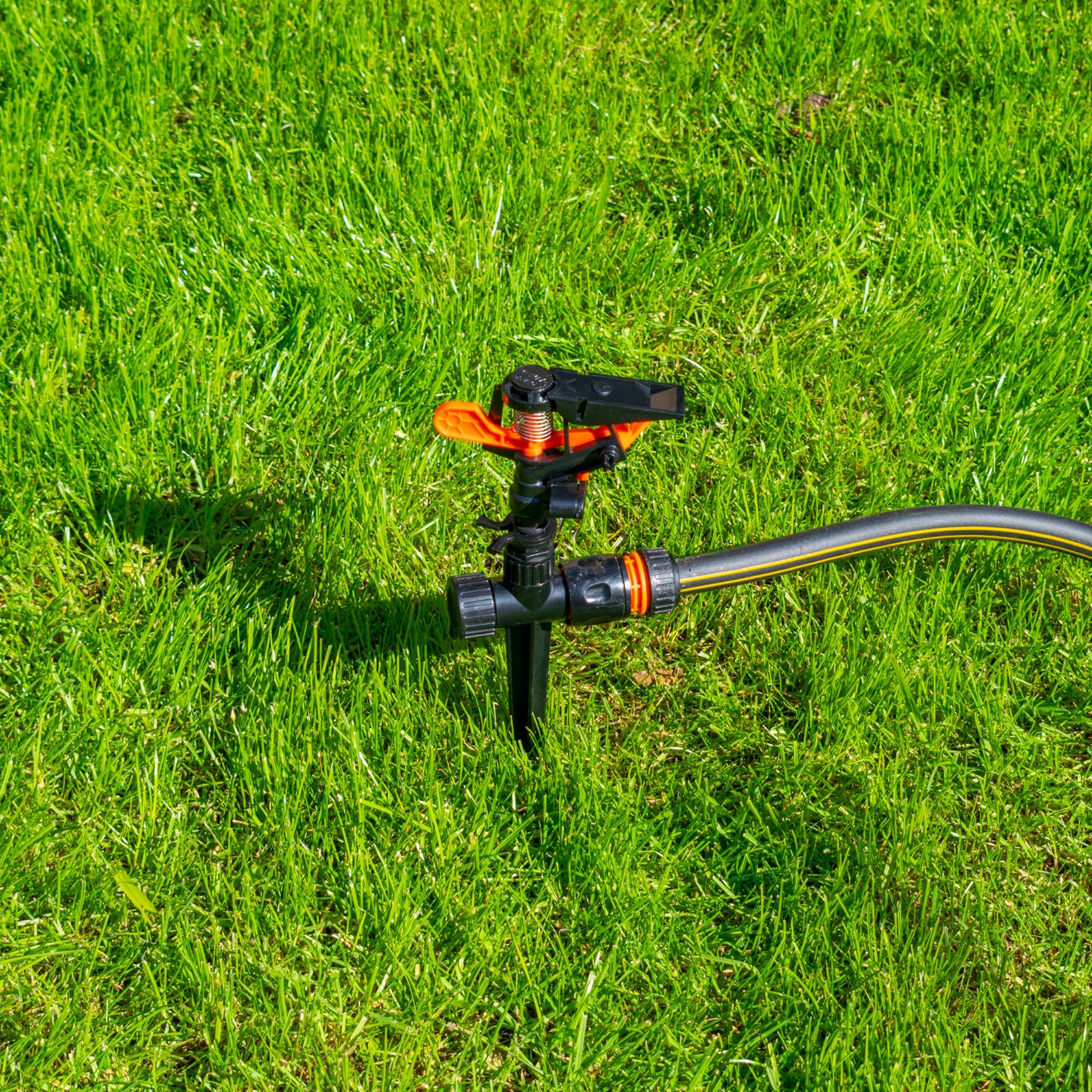 Sprinkler on spike with hose connection fitting, black and orange components