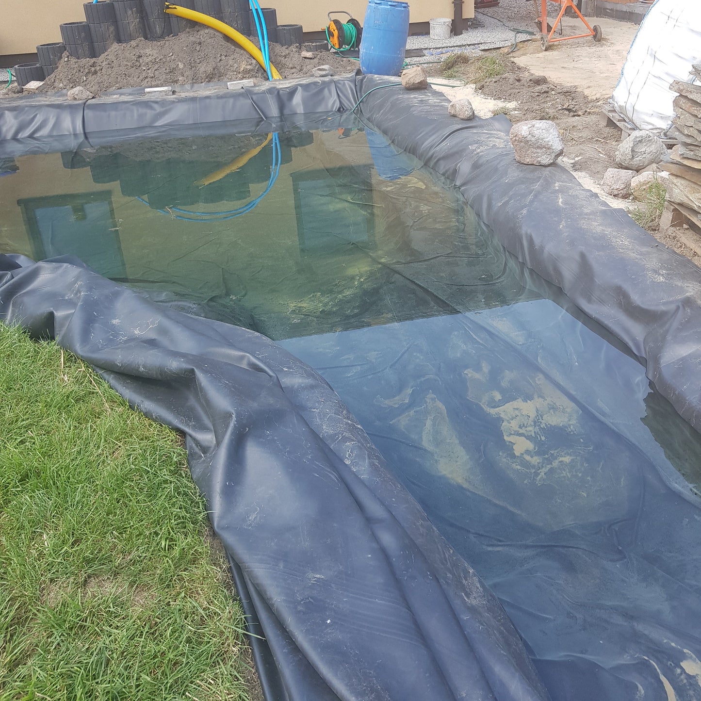 Schwarzer EPDM-Pondliner mit Unterlage, geformte Bahnen an Teichrand