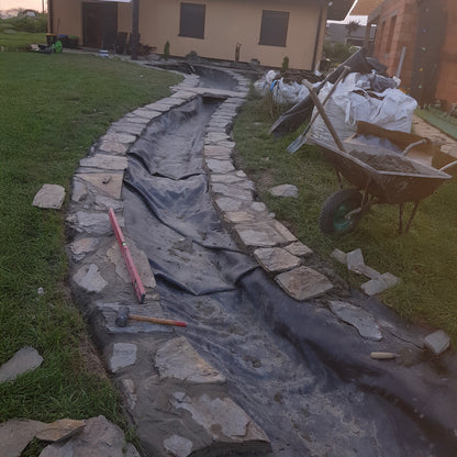 EPDM pond liner with underlay, dark grey membrane lining a rock-edged trench