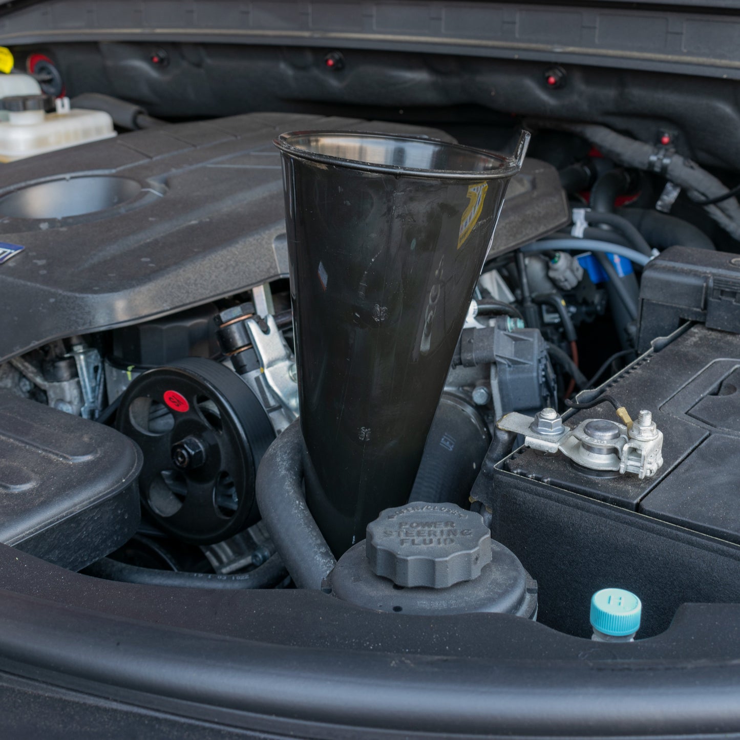 Long black funnel standing upright in car engine compartment