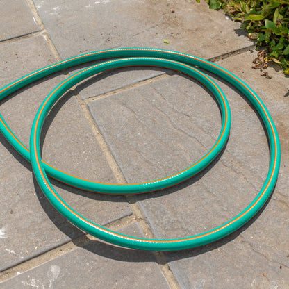 Coiled green garden hose on pavement with orange stripes along the length