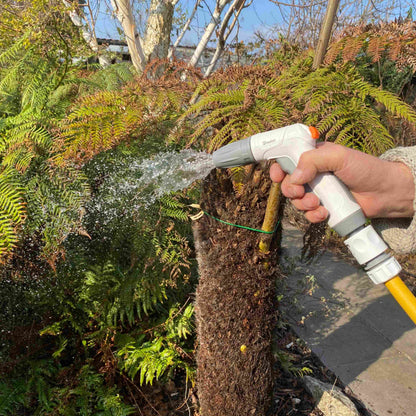 Adjustable hose water sprayer gun spraying a mist stream, held in hand