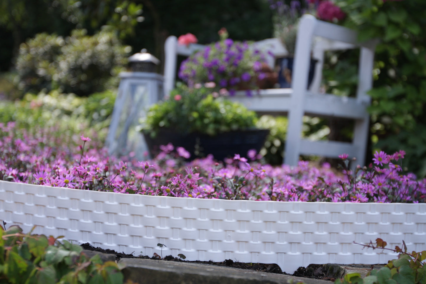 Grey rattan-effect lawn edging border separating garden flowers from soil