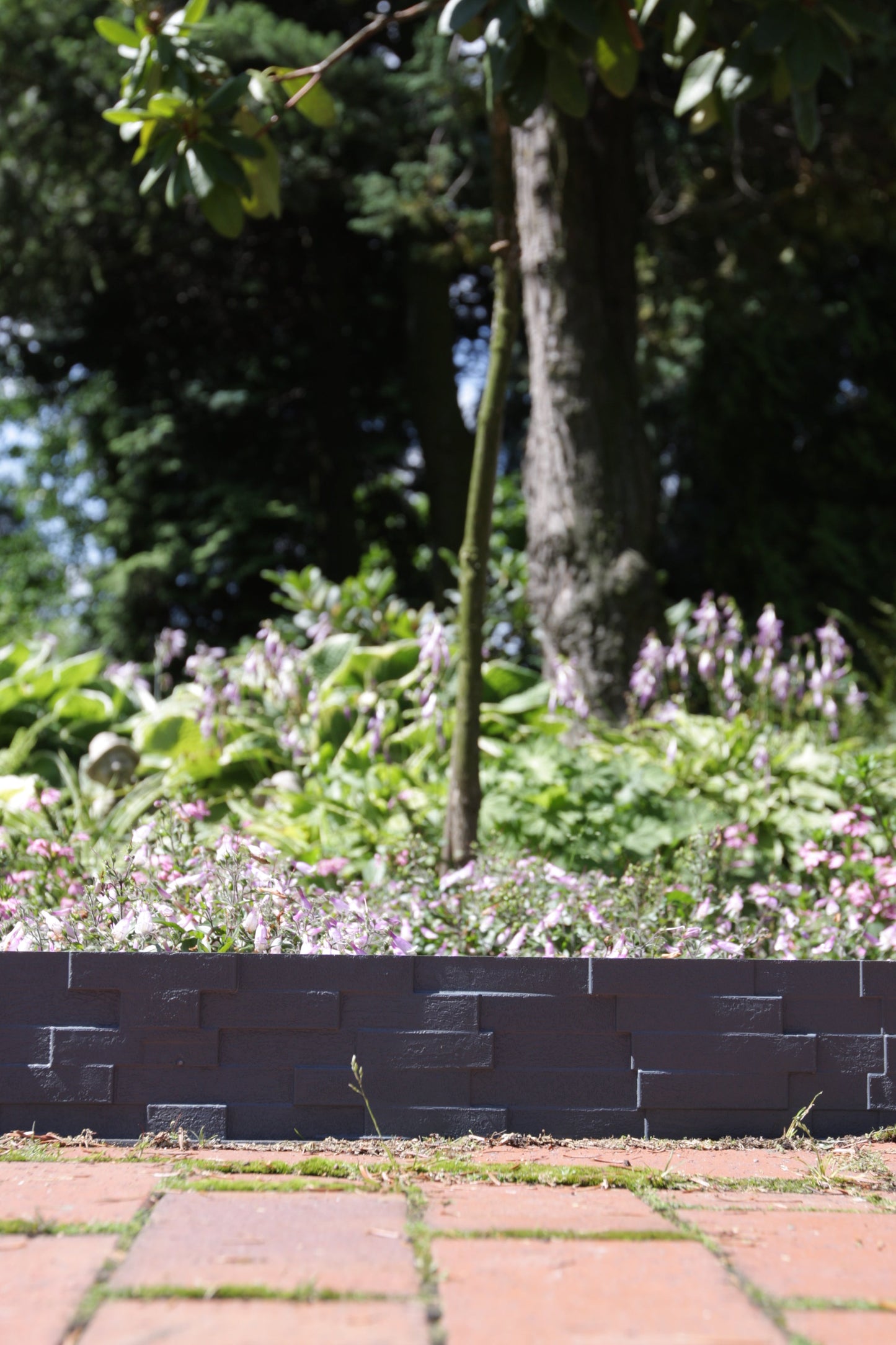 Gray plastic lawn edging with slate-effect brick pattern along garden border