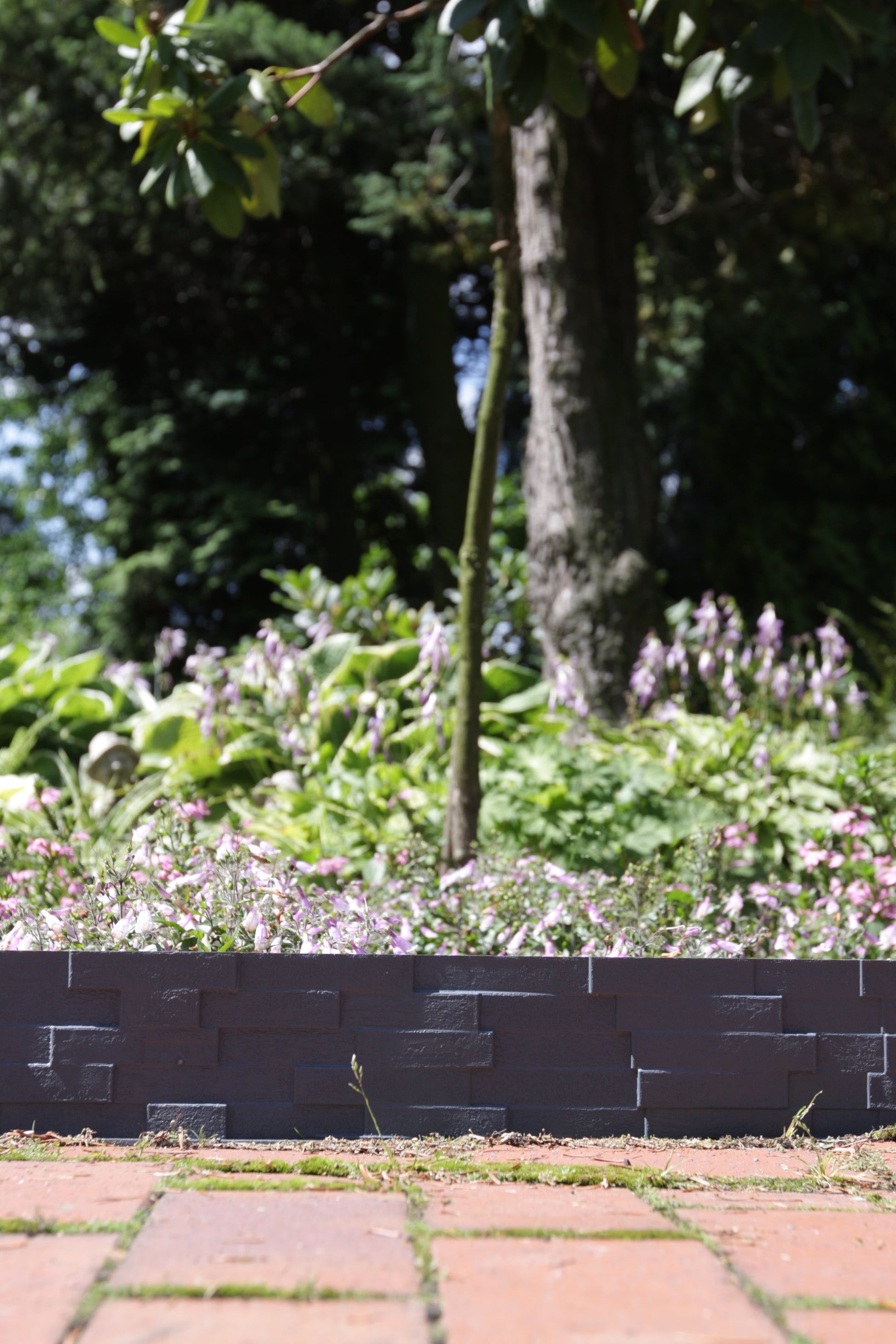 Gray plastic lawn edging with slate-effect brick pattern along garden border