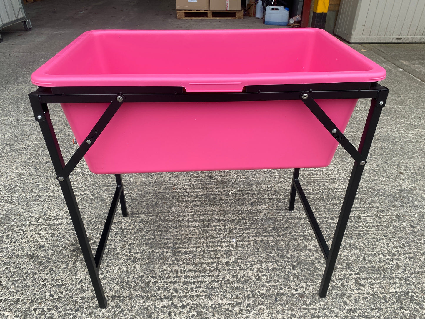 Pink dog bath tub with black stand, front view with legs and support frame
