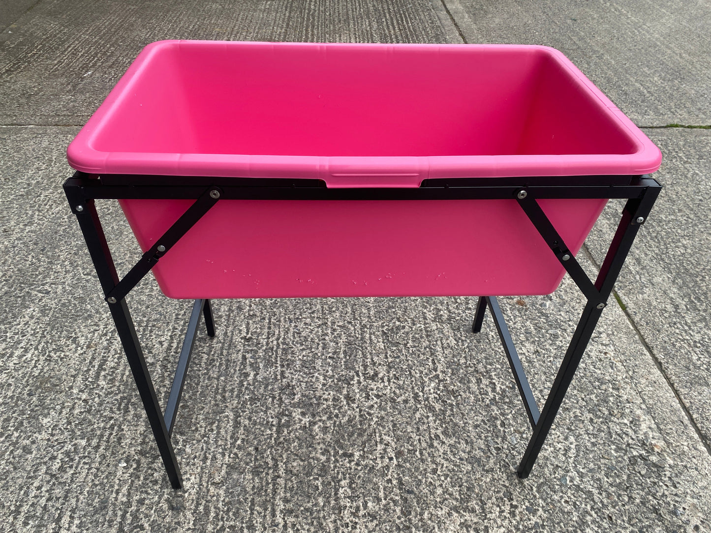 Pink dog bath on black folding stand, top rim and rectangular basin visible