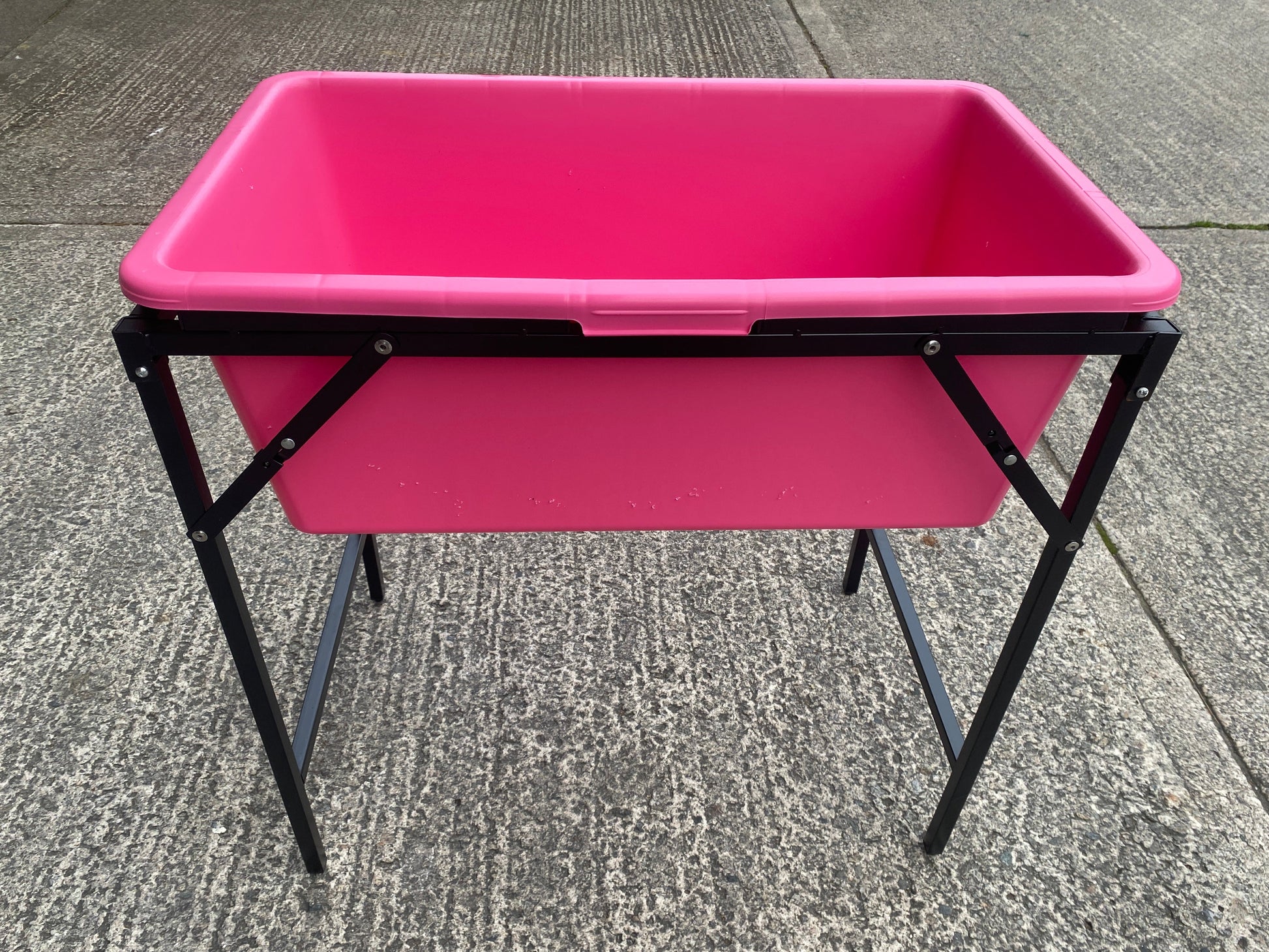 Pink dog bath on black folding stand, top rim and rectangular basin visible