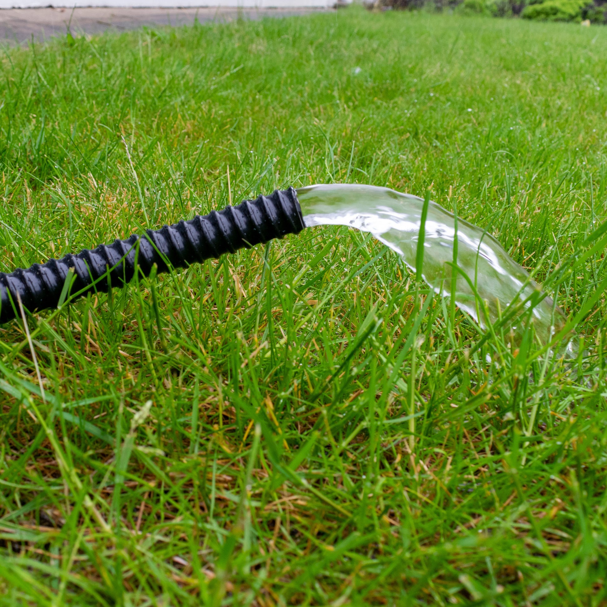 Black corrugated pipe directing water spray from the end