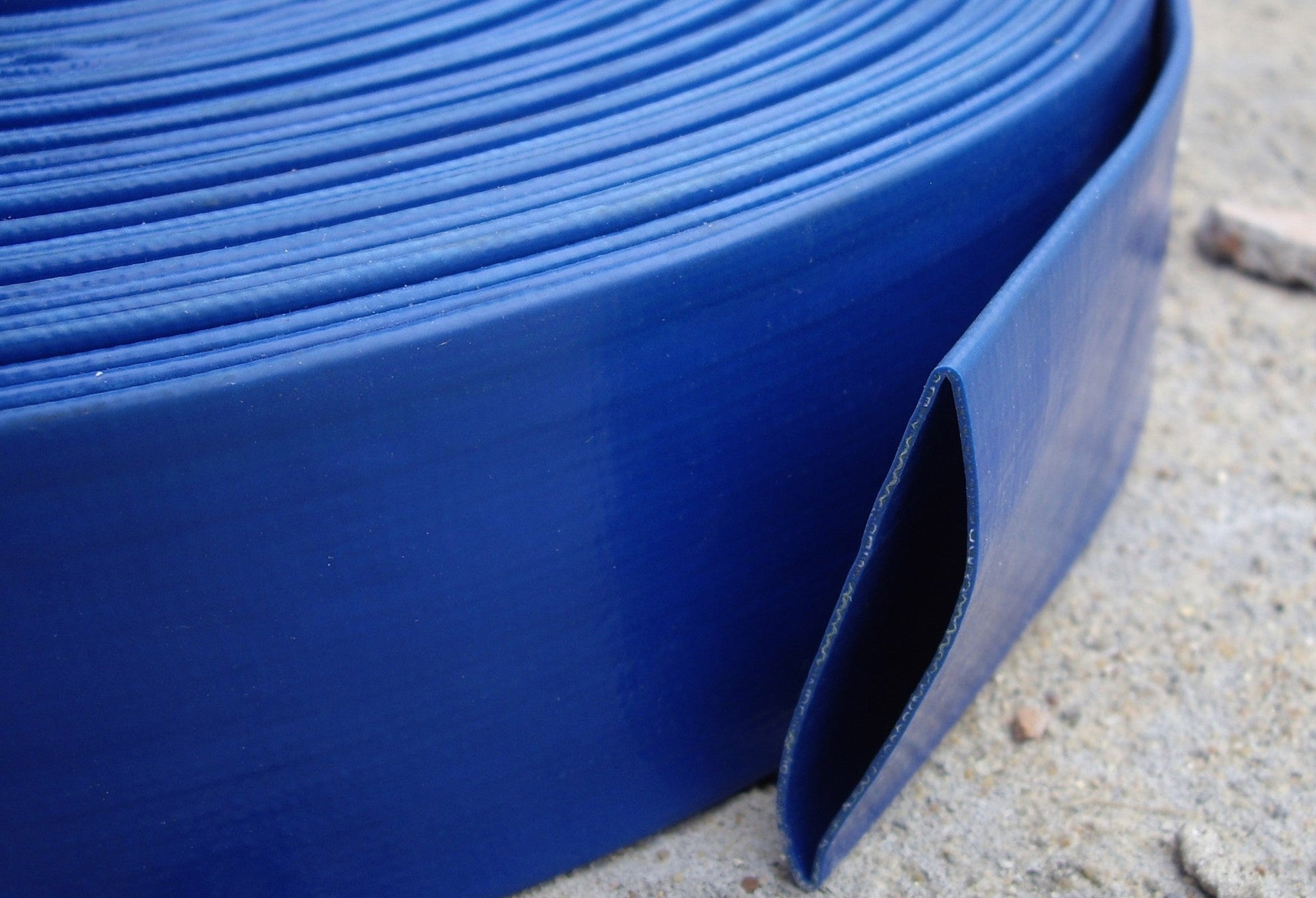 Blue lay flat 2" PVC hose section showing side edge and channel opening