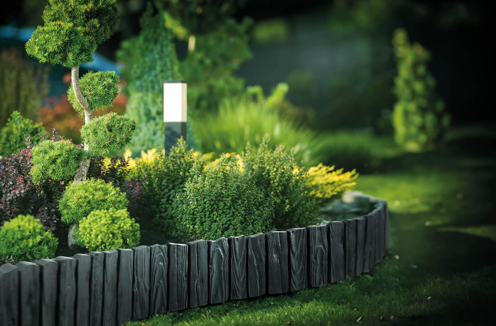 Gray plastic lawn edging curve with wood-effect panels and evenly spaced stakes