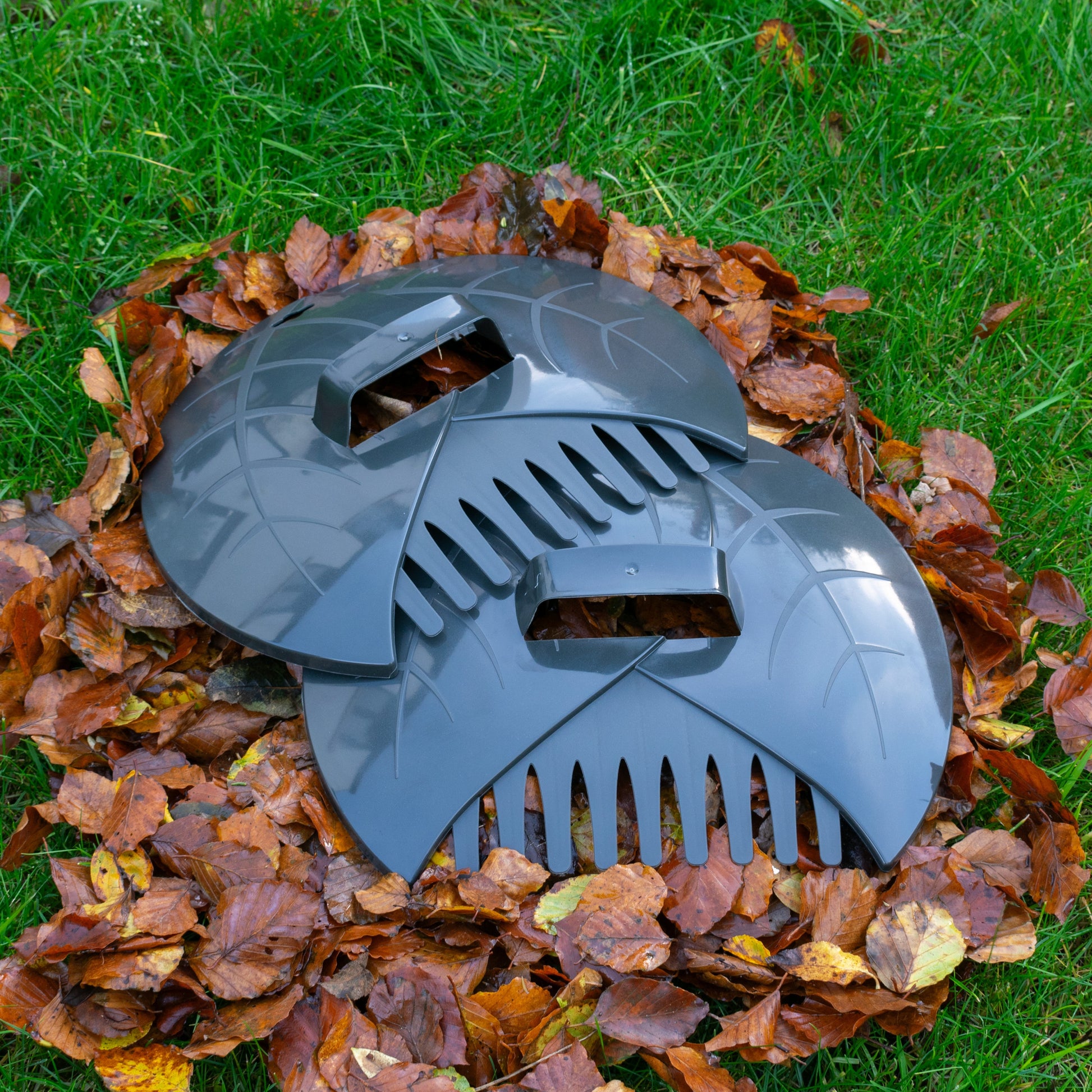 Dark gray leaf scoop with claw-like tines and curved guard for collecting leaves