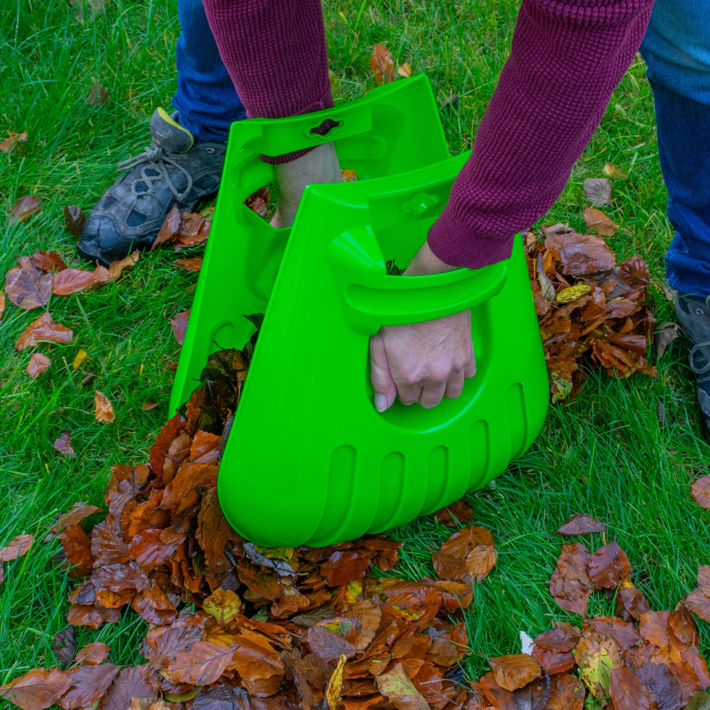 Large green leaf grab scoop in hand, ready to pick up fallen leaves on grass