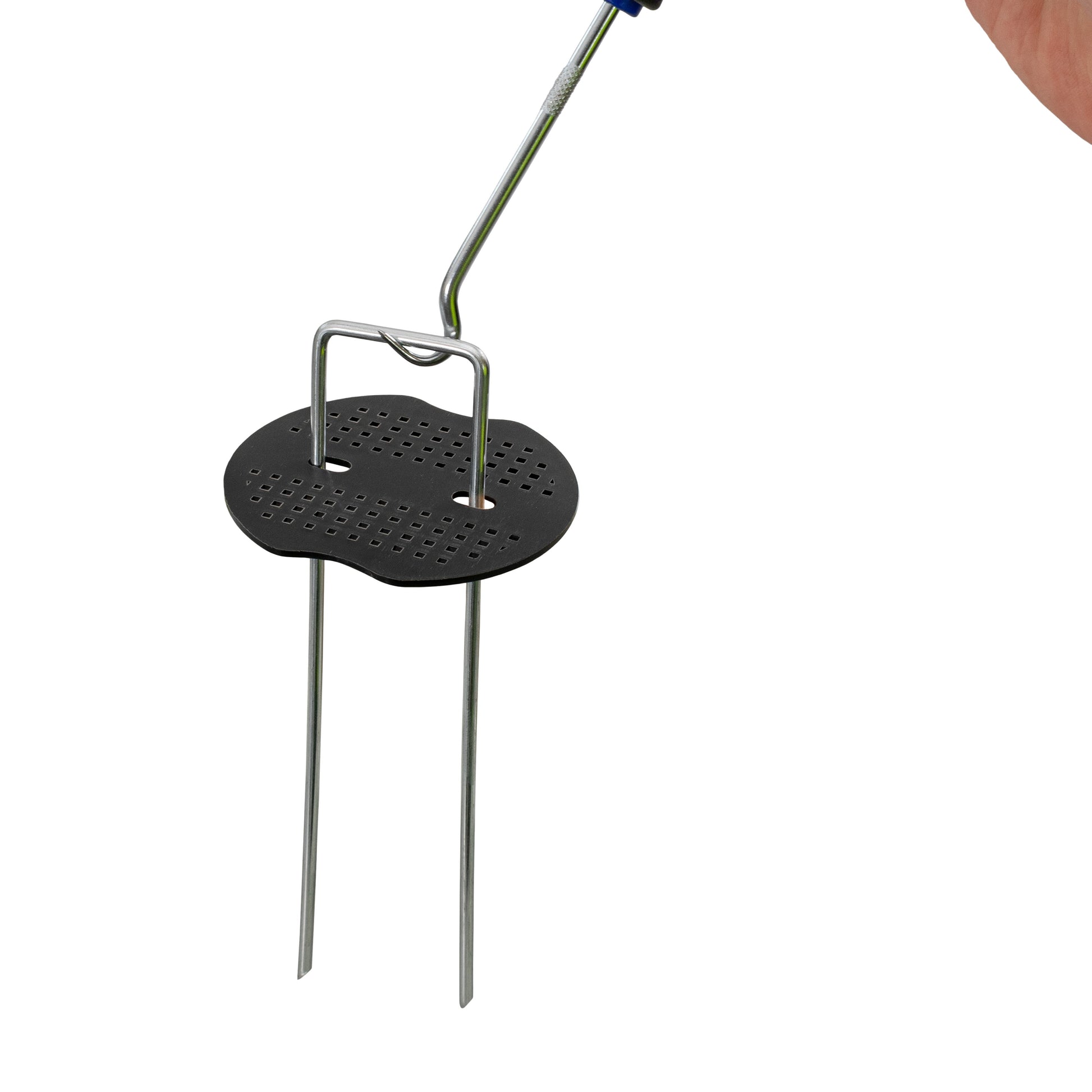 Weed control membrane peg washer installation view: black perforated base on metal pins
