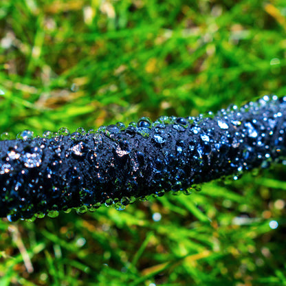 Black porous hose line with continuous beads of water along the surface