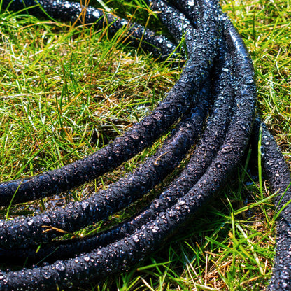 Porous soaker hose with dark blue fabric and droplets along the length