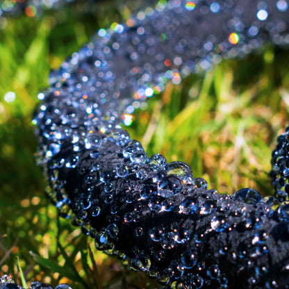 Dark porous soaker hose surface with water droplets for slow watering