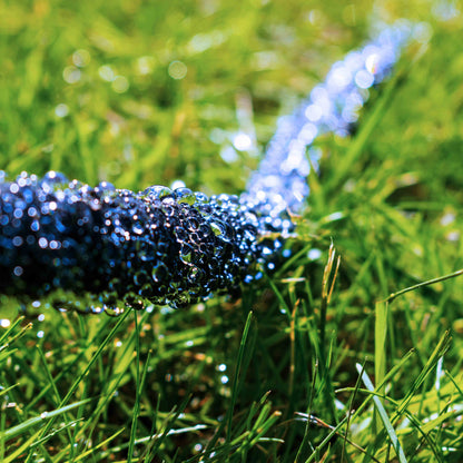 Dark soaker hose releasing water mist and beads along the length