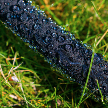 Dark porous soaker hose with water beads along the length in use