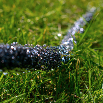 Porous soaker hose water release, dark rubber with misty droplets