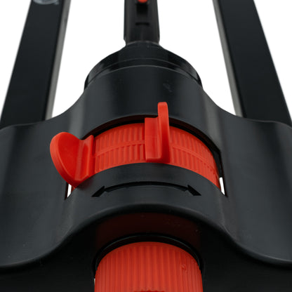 Red-orange control switch on black sprinkler head above orange ring