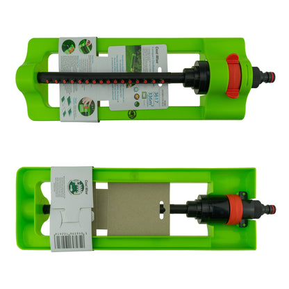 Green oscillating sprinkler with red control and hose connector, shown in packaging