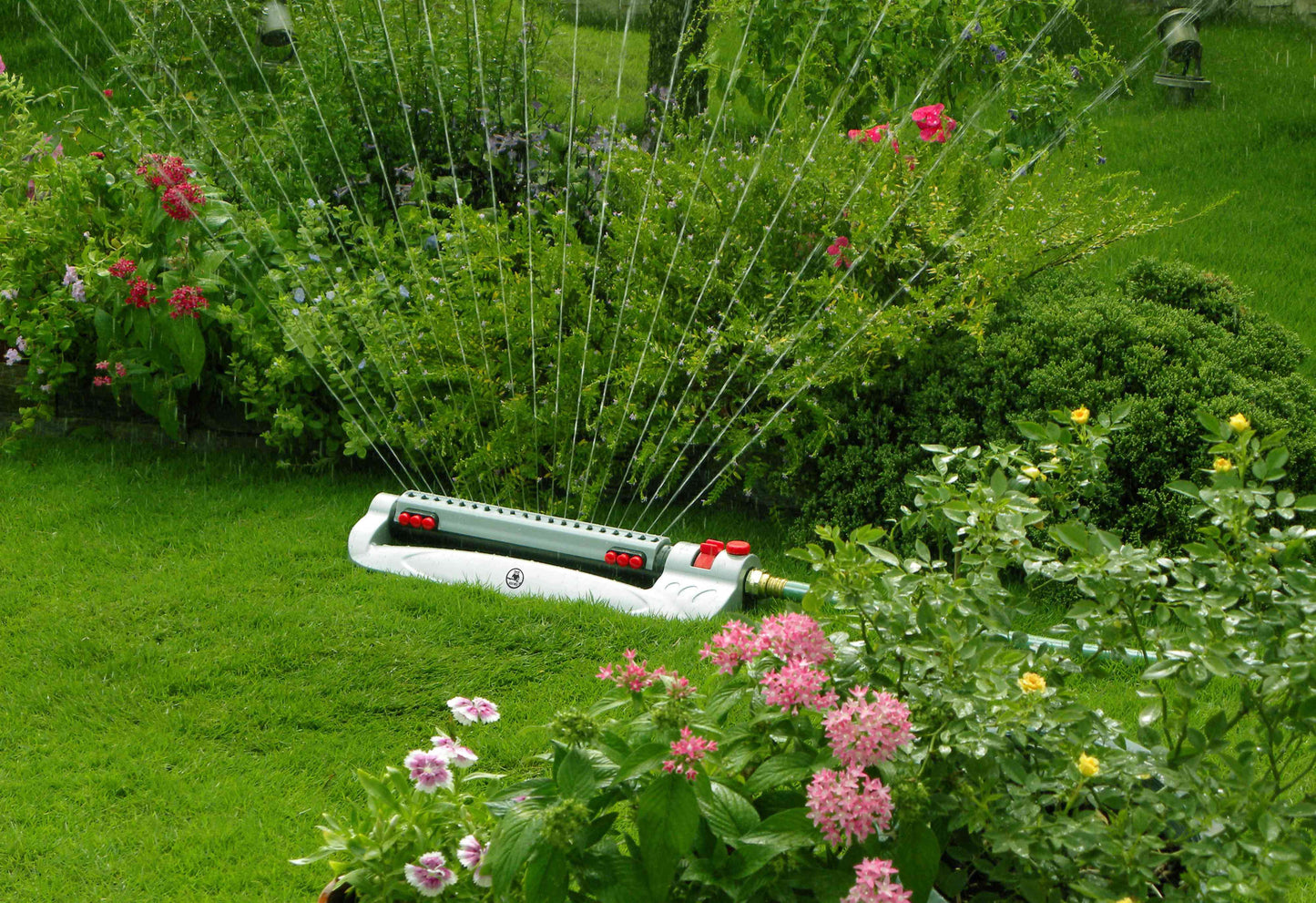 Turbo oscillating sprinkler with water spray arc, gray housing and red dial