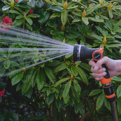 Orange-and-black hose water sprayer with wide spray stream from nozzle