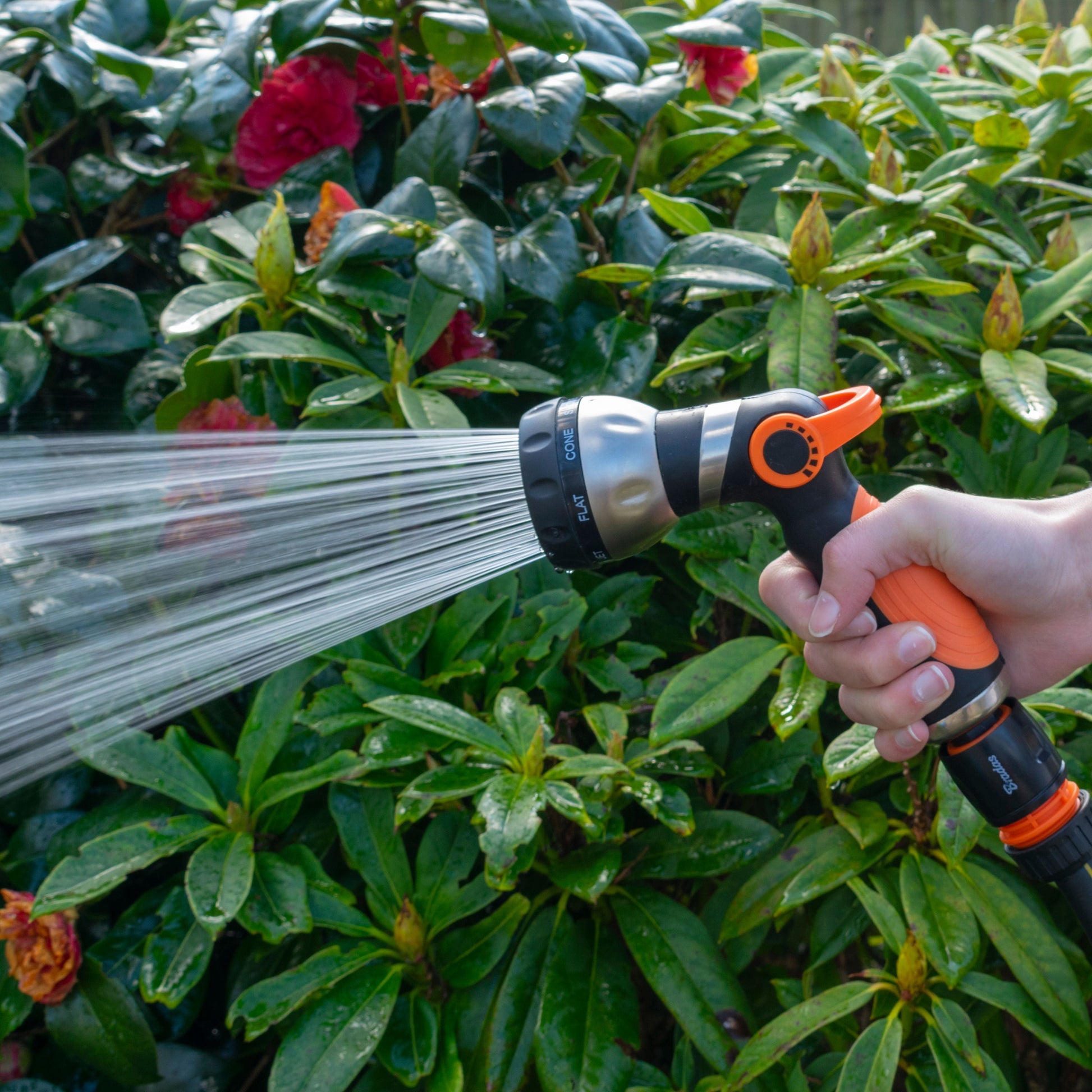 Hose sprayer gun spraying a wide fan stream from the orange nozzle head